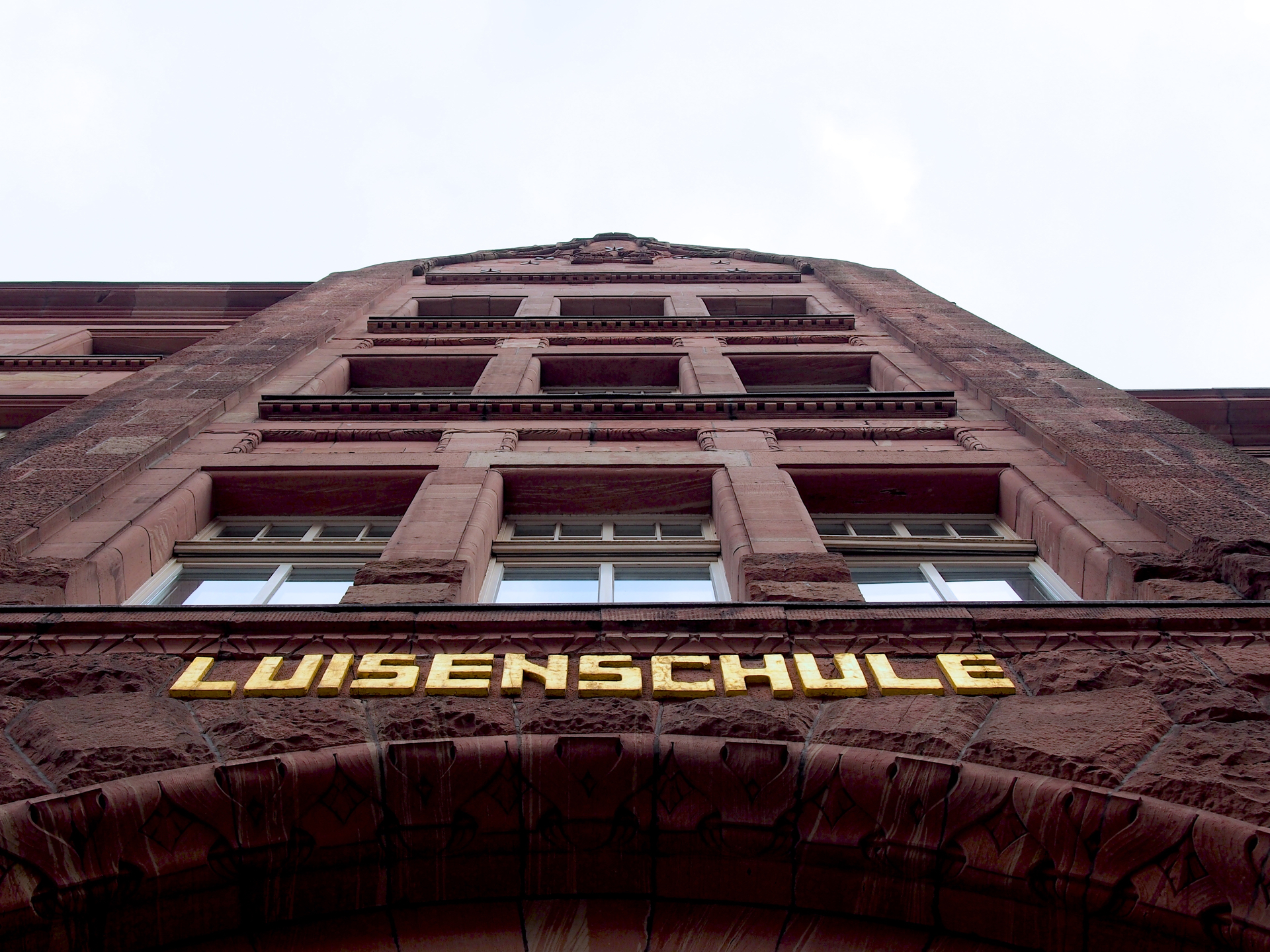 Sandsteinfassade des Luisen-Gymnasiums mit dem goldenen Schriftzug „Luisenschule“ über dem Eingang